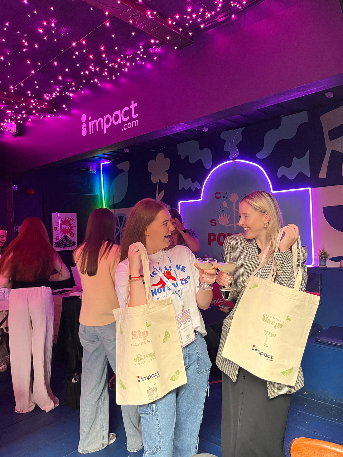 Two delegates at a conference in Manchester, proudly holding up the tote bags they hand printed at a Hoop & Fred corporate workshop and smiling to one another